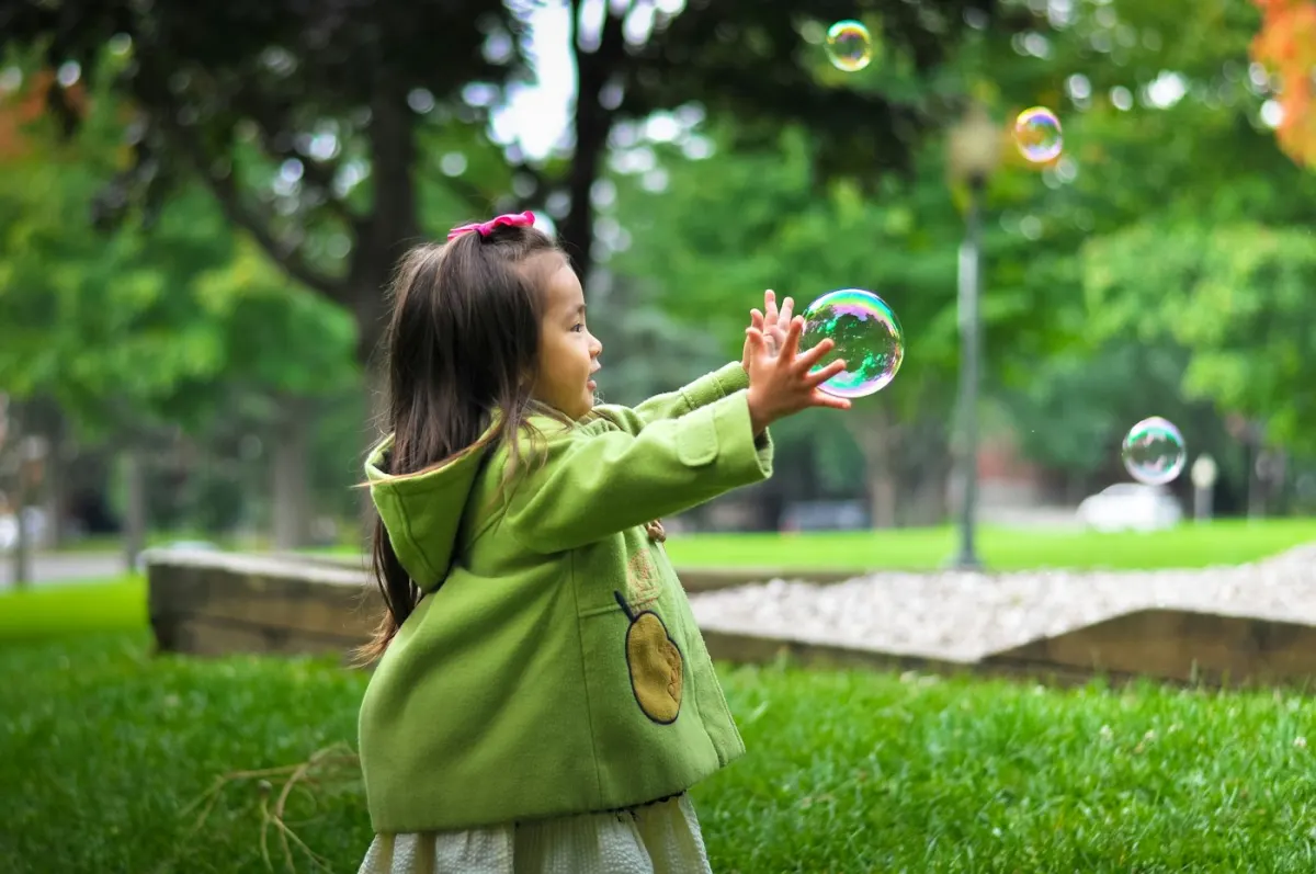 Une petite fille attrape des bulles de savon dans un jardin